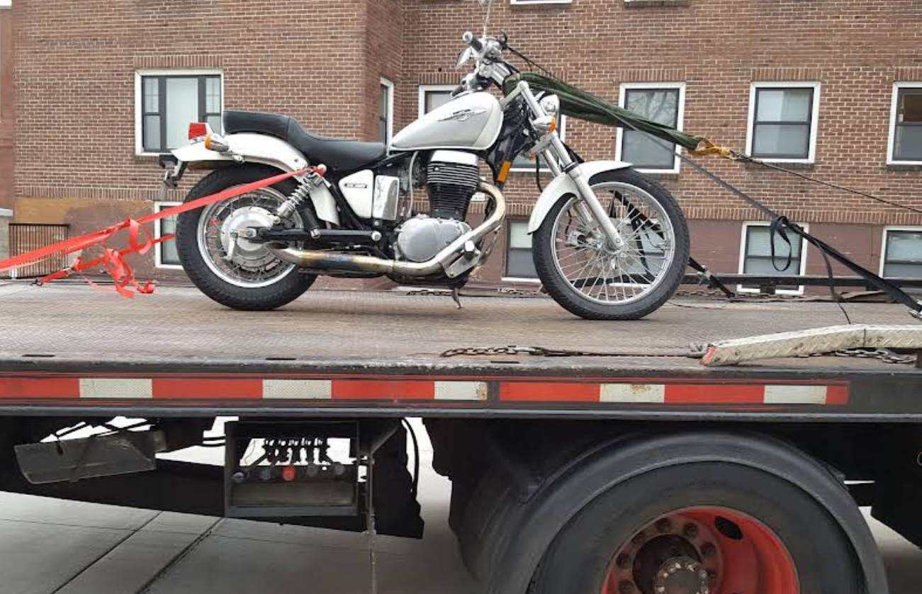 Motorcycle securely strapped to flatbed for transport